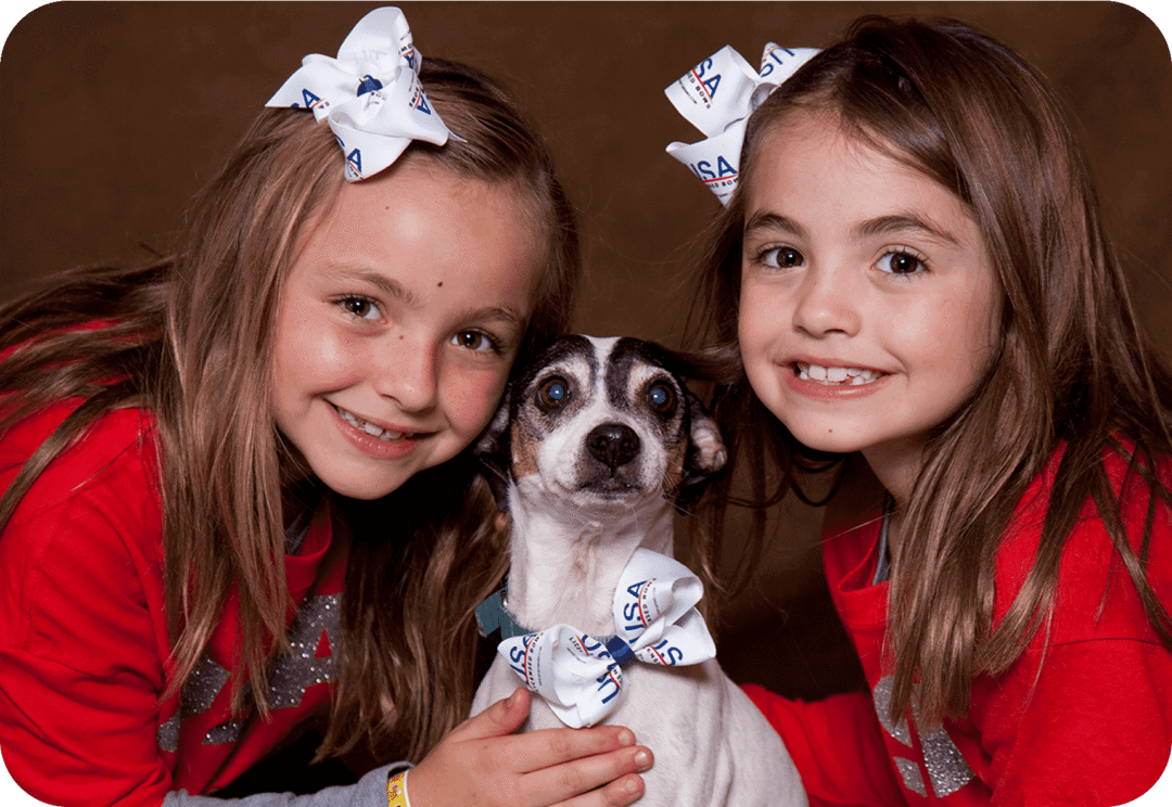 Two girls with a small dog posing.